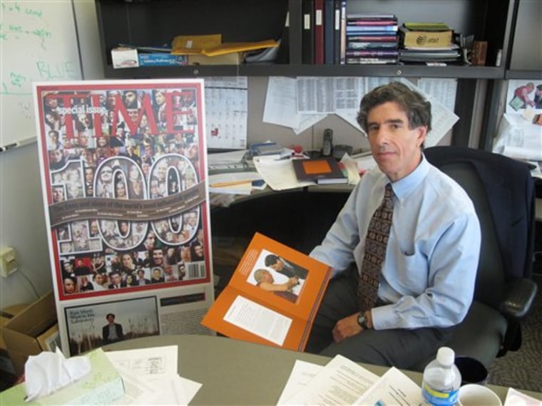 University of Wisconsin-Madison neuroscientist Richard Davidson, an expert in how meditation impacts brain functions, poses with a picture of him meeting the Dalai Lama on Wednesday, April 28, 2010 at his office in Madison, Wis. His collaboration with the Dalai Lama made him one of Time's 100 most influential people in 2006, seen left. (AP Photo/Ryan J. Foley)